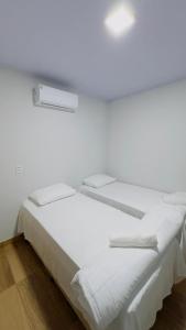 a white bedroom with two beds and a window at Hotel Luxx Sorriso in Sorriso +3 photos