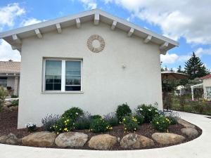 a house with a flower garden in front of it at בצל האורן Betzel haoren in El-Rom