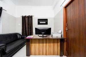 a room with a couch and a desk with a computer at Townhouse Coimbatore International Airport Formerly MK Elegance Inn in Coimbatore