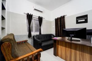 a living room with a couch and a television at Townhouse Coimbatore International Airport Formerly MK Elegance Inn in Coimbatore
