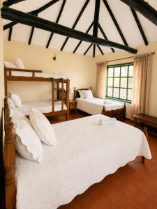 a bedroom with two beds and a large window at Hotel Altair in Villa de Leyva