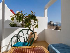 a chair and a table on a balcony with a plant at JIBARI, riad luminoso con patio en la medina de Asilah in Asilah