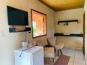 a room with a refrigerator and a tv on the wall at Veraneio Recanto dos Ipês in Pirenópolis