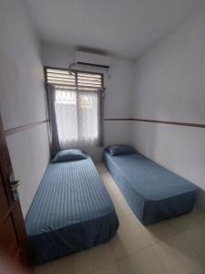 two beds in a small room with a window at Omah Diaz Homestay Malioboro in Jetis +4 photos