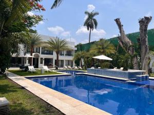 a swimming pool with palm trees and a building at Hotel Boutique Casa Ceibas in Cuautla Morelos