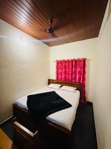 a bedroom with a bed with a red curtain at Palm paradise in Kadavoor