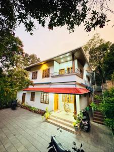 a house with a motorcycle parked in front of it at Palm paradise in Kadavoor