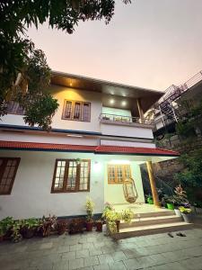 a white house with a porch and some plants at Palm paradise in Kadavoor +4 photos