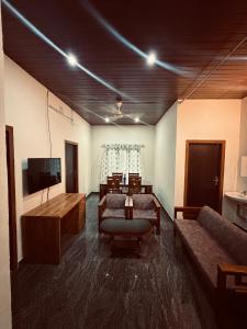 a living room with couches and a flat screen tv at Palm paradise in Kadavoor