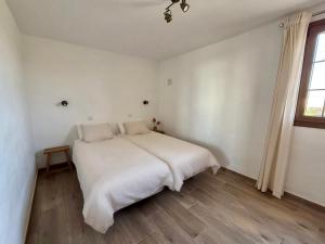 a white bed in a white room with a window at Casa Joanna Lanzarote in Nazaret