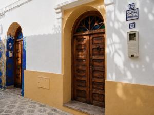 a building with a wooden door on the side of it at JIBARI, riad luminoso con patio en la medina de Asilah in Asilah +19 photos
