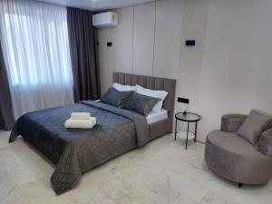 a bedroom with a bed and a chair at Премиум квартира в современном стиле in Līsakovsk