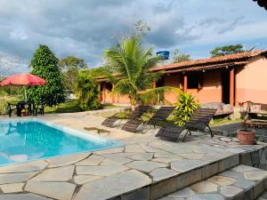 a patio with a pool and chairs and a house at Veraneio Recanto dos Ipês in Pirenópolis