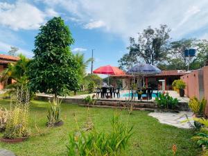 a garden with tables and umbrellas and a pool at Veraneio Recanto dos Ipês in Pirenópolis