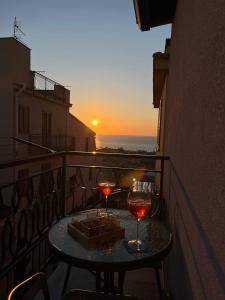 a table with two glasses of wine on a balcony with the sunset at Apartment, Sulina's House 2 in Campofelice di Roccella
