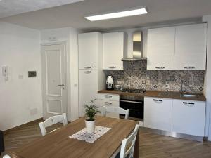 a kitchen with white cabinets and a wooden table at Apartment, Sulina's House 2 in Campofelice di Roccella