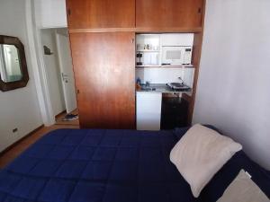 a small bedroom with a blue bed and a kitchen at SL 1908 in Olivos