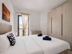 a bedroom with a large white bed and a window at Central Msida Modern Holiday Apartment in Tal-Ħriereb