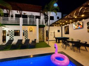 a swimming pool with a pink swan in front of a house at Pousada Jardim Mágico in Ponta Negra