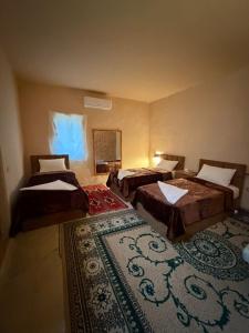 a room with three beds and a rug at Mawasem Dana in Dana