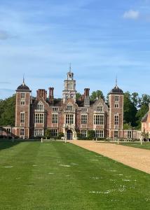 a large brick building with a grass field in front at Cuckoo Bush Cottage - A unique cottage retreat in Holt