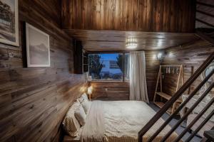 a bedroom with wooden walls and a bed with a window at Bear house Dalat in Da Thien