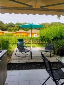 a patio with two chairs and a table with an umbrella at Appartement avec piscine et accès direct plage 102 in Folle Anse