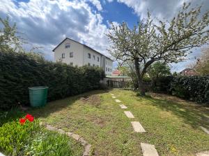 a yard with a white building and a tree at Gemütliche Maisonette nahe der längsten Burg der Welt in Burghausen