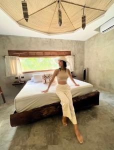 a woman sitting on a bed in a room at HOTEL ZAZIL KIN TULUM serenity & wellness in Tulum