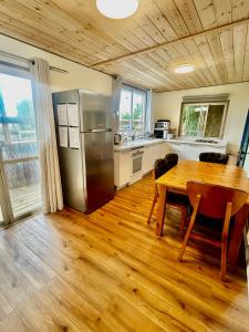 a kitchen with a table and a stainless steel refrigerator at Tzimmer B'Kfar הצימר בכפר in Kefar Pines