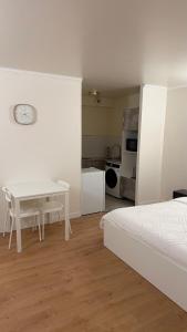 a white bedroom with a white table and a kitchen at Studio Moderne - Proche 15mn Orly et 25mn Paris in Juvisy-sur-Orge