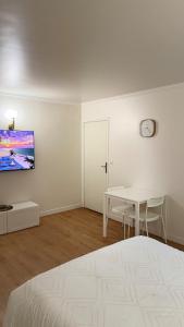 a white room with a table and a clock on the wall at Studio Moderne - Proche 15mn Orly et 25mn Paris in Juvisy-sur-Orge