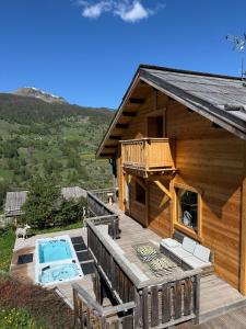 a log cabin with a deck and a swimming pool at Chalet le Chantelevent for 24 Guests - Slope Views, Pool & Jacuzzi in Vars