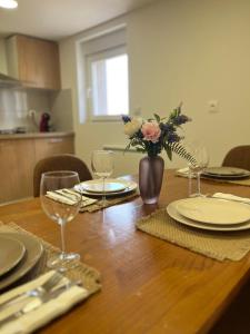 a table with plates and glasses and a vase of flowers at Cosy Appartement avec Parking in Feugarolles