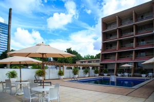 un patio del hotel con mesas y sombrillas y una piscina en Da Vinci Hotel & Conventions by Easy Hotéis, en Manaus
