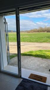 an open sliding glass door with a view of a field at Cosy Appartement avec Parking in Feugarolles