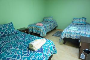 a room with two beds and a chair in it at Hostal Urenda in Los Ángeles