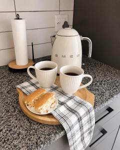 a table with two cups of coffee and a plate of bread at Garden View Suite in Gqeberha