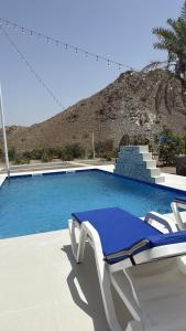 ein blauer Swimmingpool mit einem Liegestuhl daneben in der Unterkunft ALSARA HiDEAWAY in Qūr