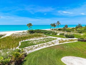 a garden with palm trees and the ocean in the background at Kings Crown 118 in Sanibel