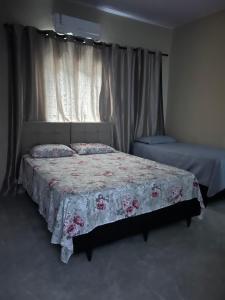 a bedroom with a bed with a floral bedspread at Casa Morada Nobre2 in Barreirinhas