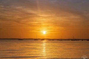 a sunset over a body of water with boats at Chez Malika in Oulad el Guern