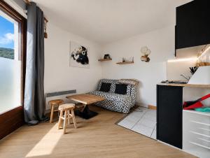 a small living room with a table and a couch at Le refuge des sportifs - studio cosy jardin - wifi in Mijoux