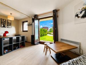 a room with a table and a large window at Le refuge des sportifs - studio cosy jardin - wifi in Mijoux