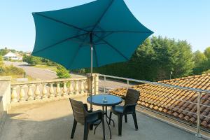 a table and chairs with a blue umbrella on a balcony at Ma Bulle Confort in Pouzauges