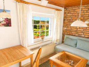 a living room with a couch and a table and a window at Reetdachtraum in Middelhagen