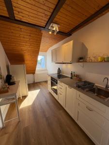 a kitchen with white cabinets and a wooden ceiling at Ferienwohnung Bergblick Bad Staffelstein in Bad Staffelstein