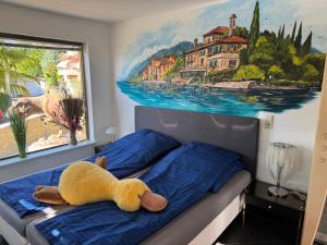 a yellow stuffed animal laying on a bed with a painting at Casa Kovacs in Herbolzheim +75 photos