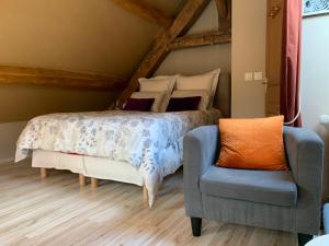 a bedroom with a bed and a blue chair at Mini duplex la Révière in Saintines