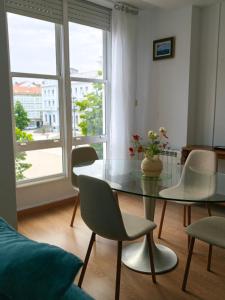 a dining room with a glass table and chairs at Apartamento Leal Ferrol in Ferrol